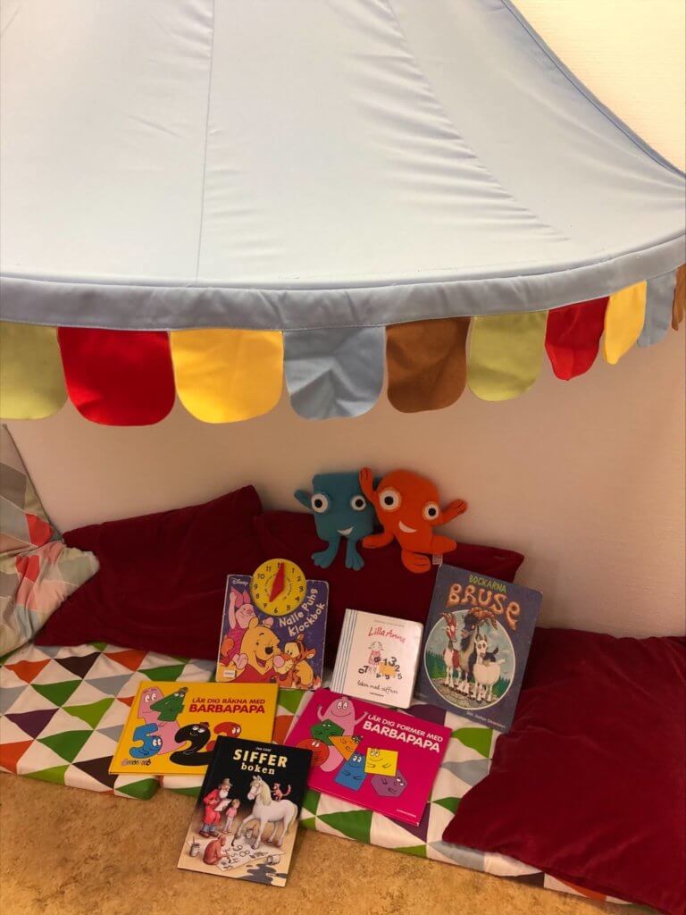 Öppen förskola läshörna under tältduk med kuddar lärvänner och böcker