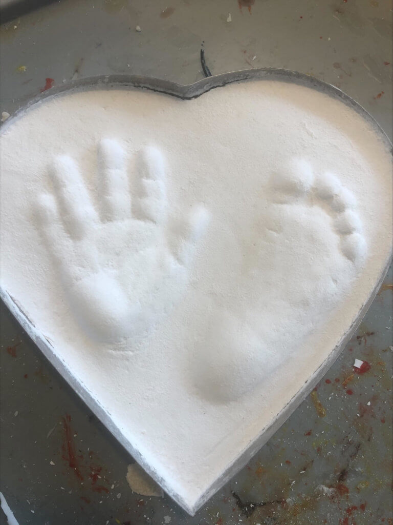 hand och fotavtryck har stelnat i vit hjärteform